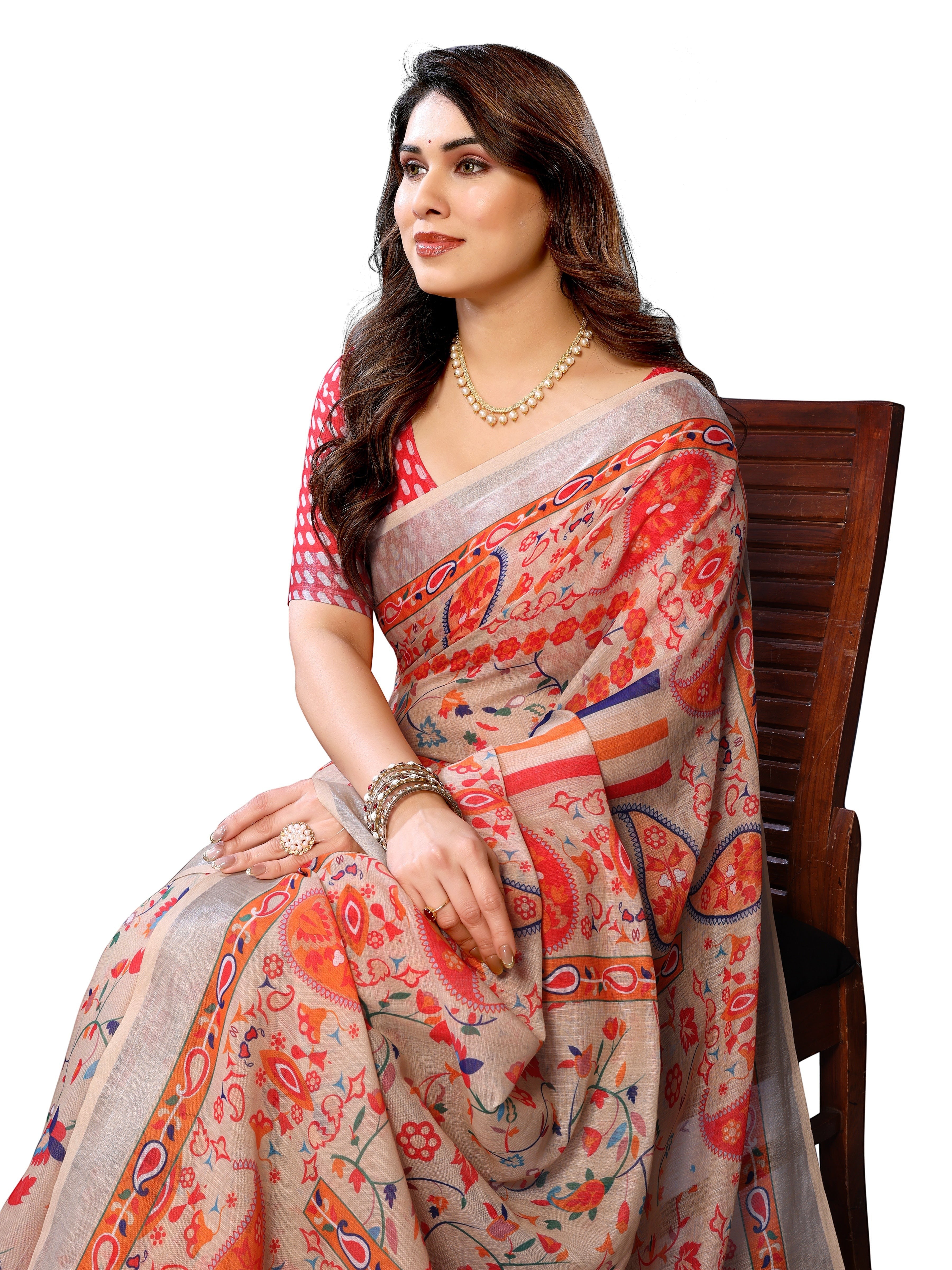 NxWear Fashion beige linen saree with orange, red, and blue floral paisley print. Model wears pearl necklace and bangles.