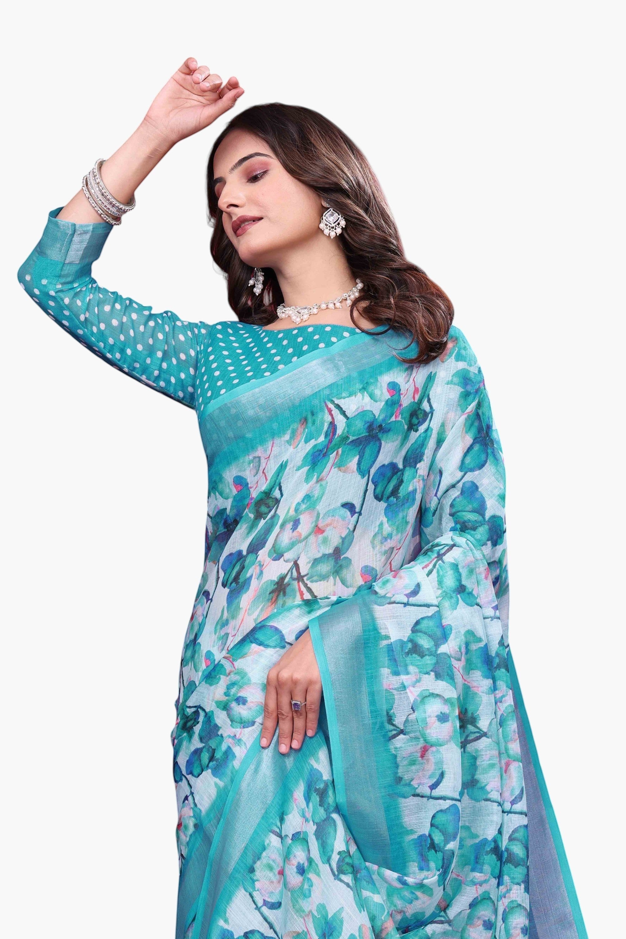 NxWear Fashion teal linen saree with a white base and blue-green floral print. Features a contrasting teal border and polka dot sleeves.
